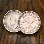 1943 Australian half penny cufflinks in rose gold bezels, kangaroo side and George VI portrait, on dark wood