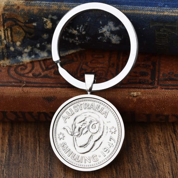 1947 Australian shilling keyring, ram's head design in a polished silver bezel, on an old leather book