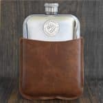 1948 Australian shilling set into the front of a polished hip flask, in a brown leather sleeve