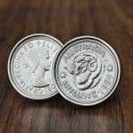 Pair of 1954 Australian shilling cufflinks in silver bezels, ram's head reverse facing out, on dark wood