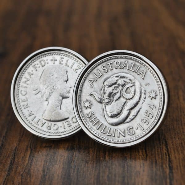 Pair of 1954 Australian shilling cufflinks in silver bezels, ram's head reverse facing out, on dark wood