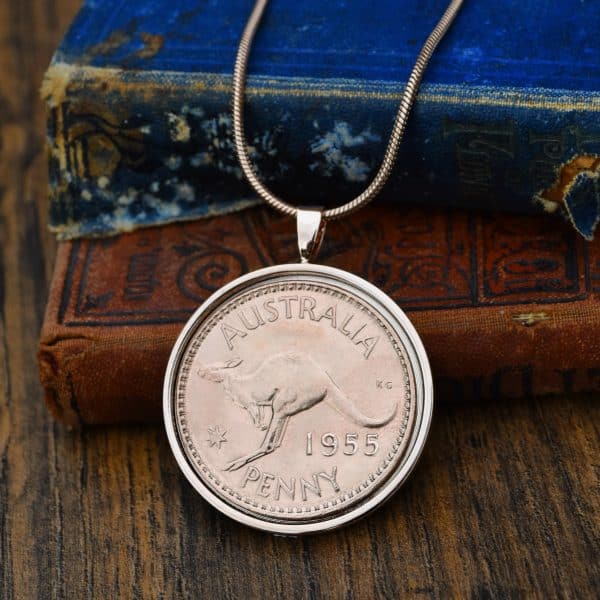 1955 Australian penny with kangaroo reverse in a silver-tone pendant bezel on a snake chain, on old books