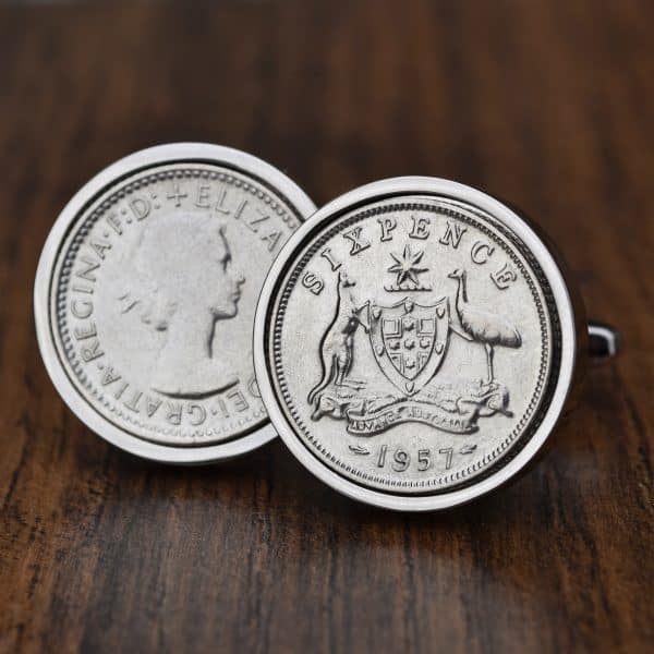 Pair of 1957 Australian sixpence cufflinks in silver bezels, coat of arms facing out, on dark wood