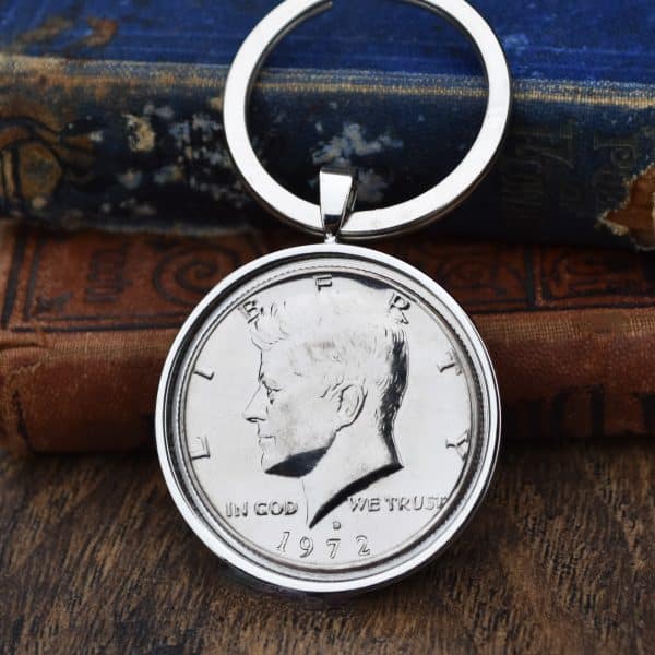 1972 United States half dollar in a silver-coloured bezel on a split-ring keyring, against old books