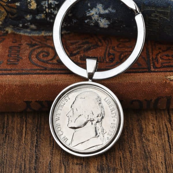 1972 USA Jefferson nickel set in a silver-tone keyring bezel, resting on a brown leather book