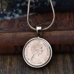1978 Australian coin in a silver-tone bezel on a snake chain, against an old leather-bound book