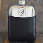 1981 United States half dollar with Kennedy portrait set into a pewter hip flask in a black leather sleeve
