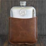Polished pewter hip flask in a tan leather sleeve, 1985 United States quarter set into the front