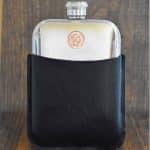 Small copper 1988 Australian 2 cent coin set into the front of a polished pewter hip flask in a black leather sleeve