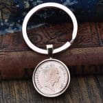1991 Australian coin in a rose gold-tone bezel and split-ring keyring, on an old leather-bound book