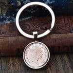 1992 Australian coin in a rose gold-tone bezel and split-ring keyring, on an old leather-bound book