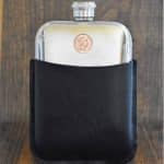 Small copper 1992 Australian 2 cent coin set into the front of a polished pewter hip flask in a black leather sleeve