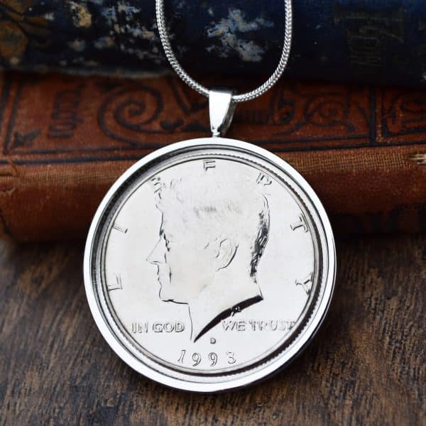 1993 American Kennedy half dollar in a silver round bezel on a snake chain, hung against antique books