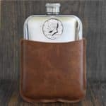 1994 United States half dollar with Kennedy portrait set into a pewter hip flask in a brown leather sleeve