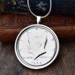 1994 American Kennedy half dollar in a silver round bezel on a snake chain, hung against antique books