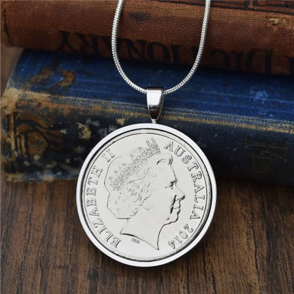Australian coin dated 2014 in a polished silver-tone pendant setting, Elizabeth II obverse, resting on antique books