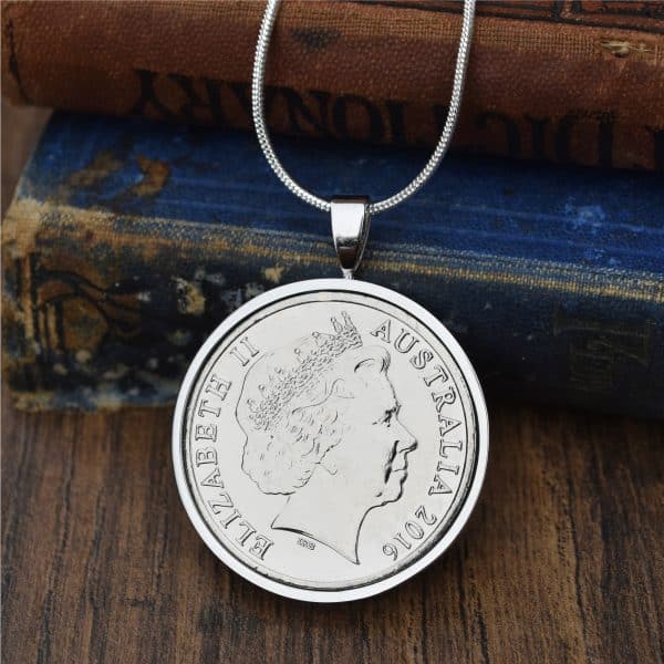 Australian coin dated 2016 in a polished silver-tone pendant setting, Elizabeth II obverse, resting on antique books