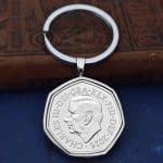 2026 seven-sided fifty pence in a silver bezel on a split ring keyring, resting on old books