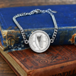 1934 Saorstat Eireann harp coin set in a silver-tone bezel on a curb link bracelet, on faded blue and red books