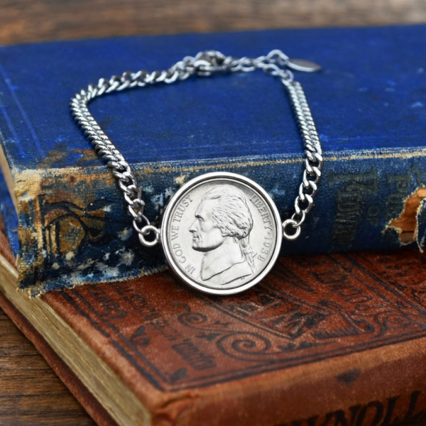 1938 US nickel coin bracelet, silver-coloured bezel and curb chain, photographed on old hardback books