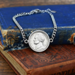 1942 US nickel coin bracelet, silver-coloured bezel and curb chain, photographed on old hardback books