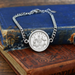 1948 Australian sixpence with kangaroo and emu coat of arms in a silver-tone bracelet on old books