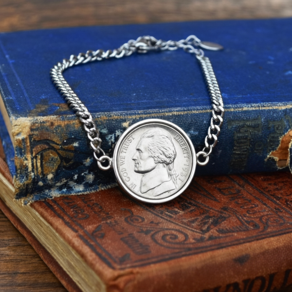 Curb chain bracelet with a 1951 US nickel set in a silver-coloured bezel, on an old blue and tan book