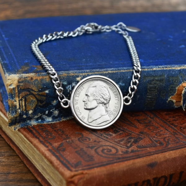 1952 Jefferson nickel bracelet, silver-coloured bezel and curb chain, laid over a faded blue book cover