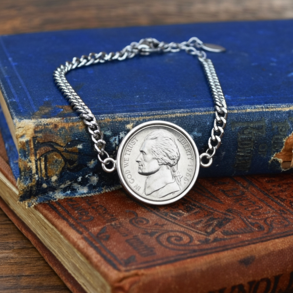 1966 US nickel in a silver-coloured bezel on a curb chain bracelet, resting on old blue and red cloth books