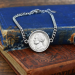 1976 US five cent coin in a silver-coloured bezel on a chain bracelet, propped on a faded blue hardback