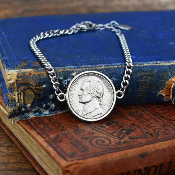 1977 nickel bracelet, Jefferson head in a silver-coloured bezel between curb chain links, on a blue book