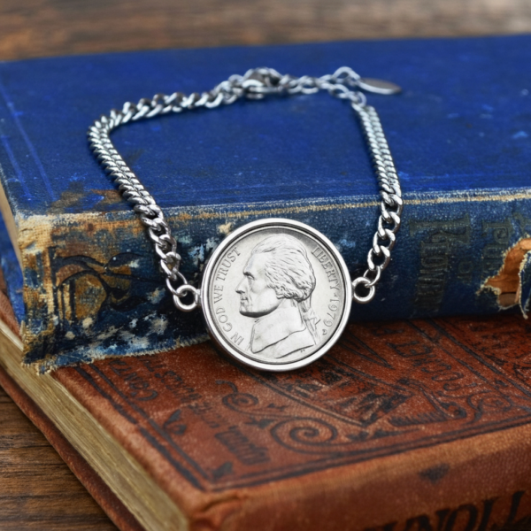 1979 US nickel set in a silver-coloured bezel on a curb chain bracelet, resting on worn blue and brown books