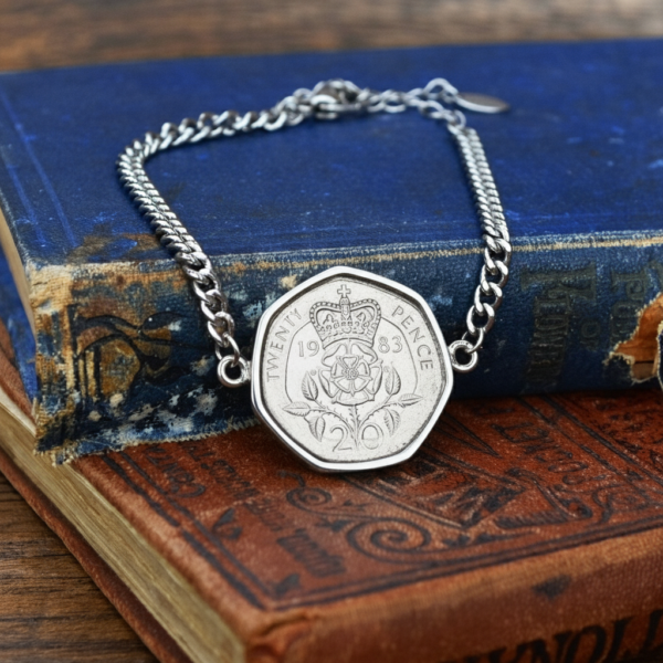 1983 twenty pence coin bracelet on a silver-coloured curb chain, crowned Tudor rose facing up, resting on old cloth-bound books