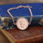 Australian 1986 coin with Queen Elizabeth II portrait, mounted in a rose gold-tone chain bracelet on old books