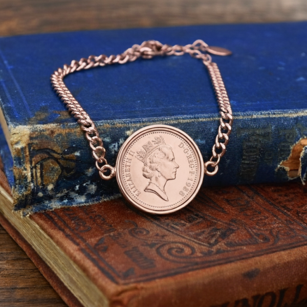 1988 one penny bracelet in rose gold, coin and curb chain laid at an angle across two old cloth books