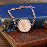 Australian coin dated 1989 with Elizabeth II portrait, in a rose gold-tone bracelet bezel on old blue and red books