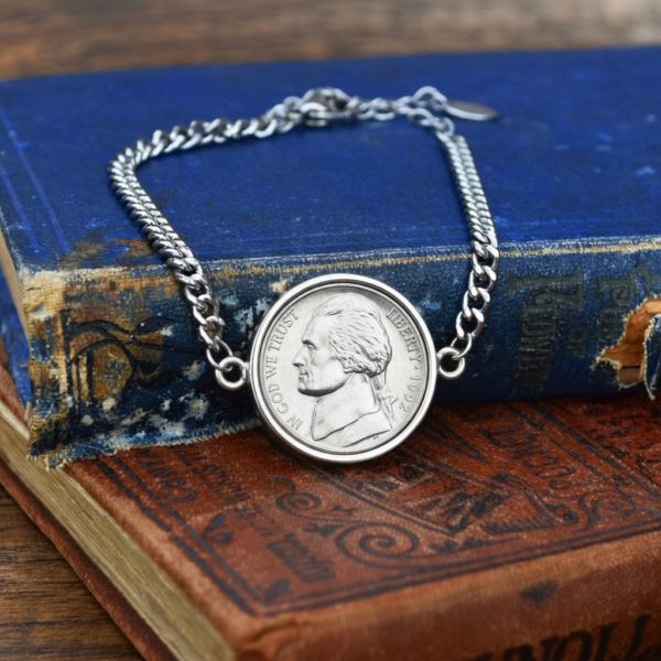 1992 US five cent coin in a silver-coloured bezel, chain bracelet arranged on two aged hardbacks