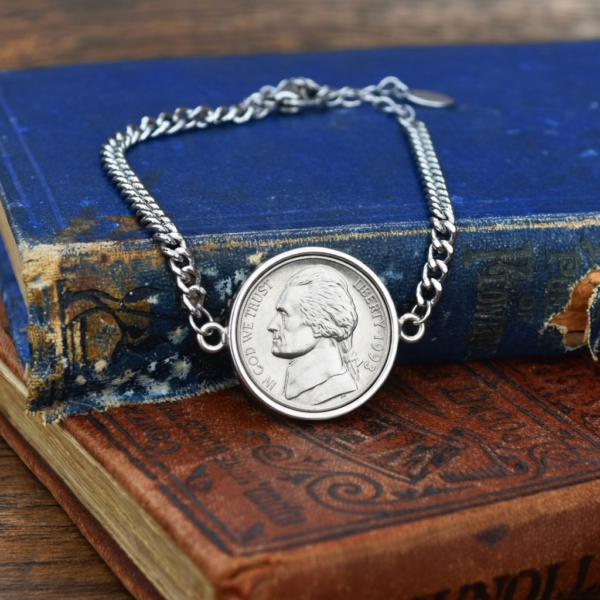 1993 US nickel in a silver-coloured bezel on a curb chain bracelet, laid over two worn antique books