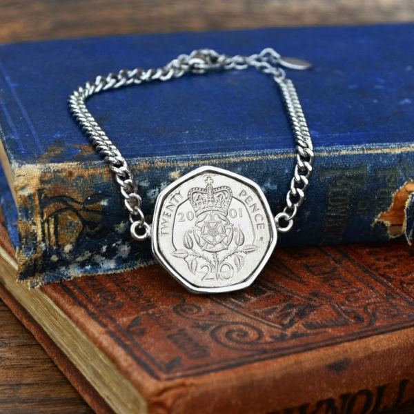 2001 twenty pence in a silver-coloured bracelet, crowned Tudor rose and date facing up, on old books