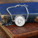 2001 US dime in a silver-coloured bezel on a curb chain bracelet, resting on worn antique books