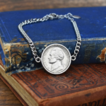 2003 US nickel set in a silver-coloured bezel on a silver curb chain bracelet, resting on old blue and brown books