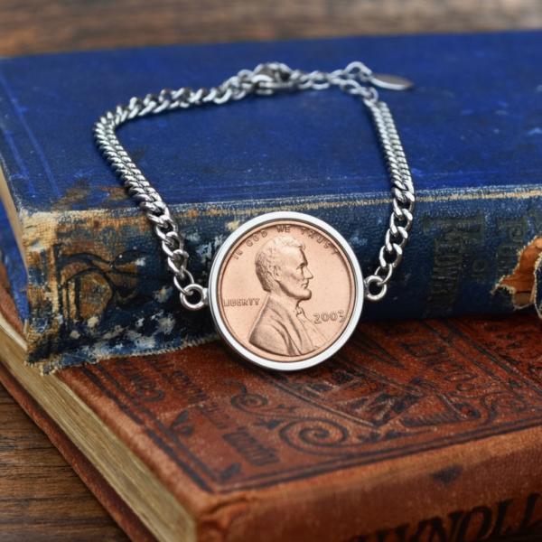 2003 US penny in a silver-coloured bezel on a curb chain bracelet, on aged blue and brown book covers