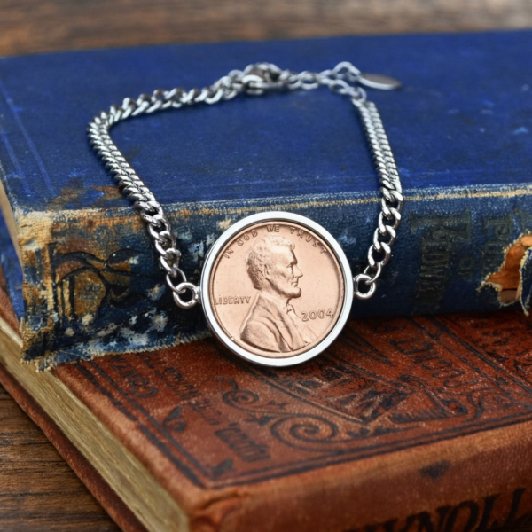2004 US penny bracelet in a silver-coloured setting, chain looped over a stack of old hardback books
