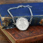 2006 twenty pence in a silver-coloured bracelet, crowned Tudor rose and date facing up, on old books