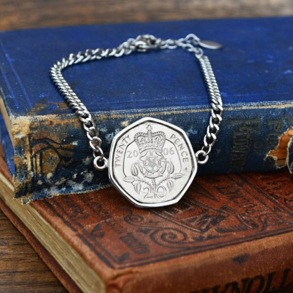 2006 twenty pence in a silver-coloured bracelet, crowned Tudor rose and date facing up, on old books