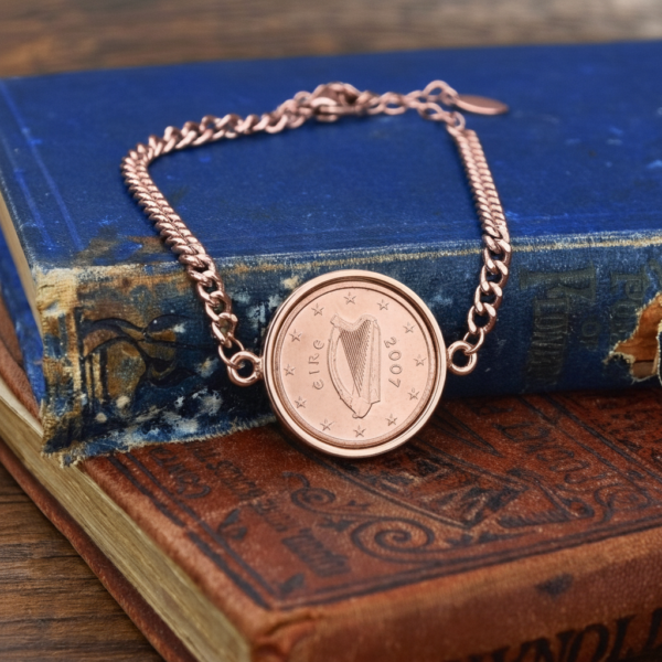 2007 Irish euro cent, harp ringed by twelve stars, in a rose gold-tone bracelet on old blue and tan books