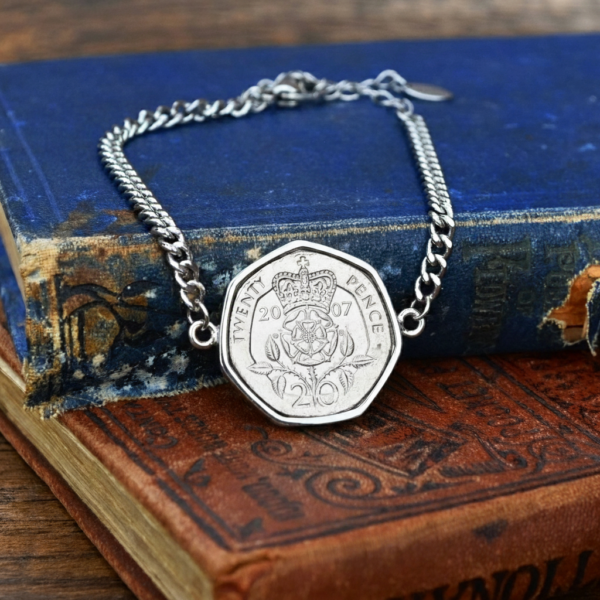 2007 twenty pence in a silver-coloured bracelet, crowned Tudor rose and date facing up, on old books