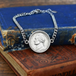 2007 US nickel in a silver-coloured bezel on a curb chain bracelet, resting on blue and brown hardback books