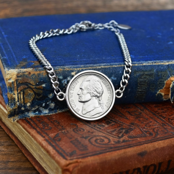 2007 US nickel in a silver-coloured bezel on a curb chain bracelet, resting on blue and brown hardback books