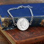 Australian coin dated 2010 with Elizabeth II portrait, set into a silver-tone curb chain bracelet on old blue and red books